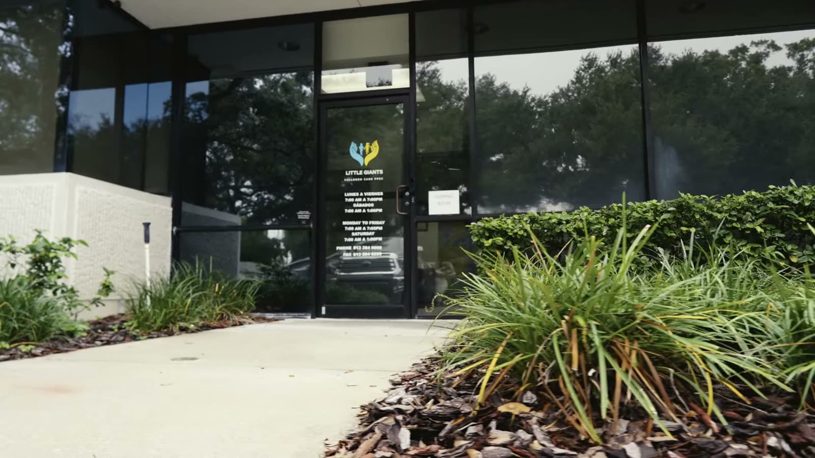 The glass front entrance of Little Giants PPEC in Tampa, with the Little Giants logo and opening hours on the door