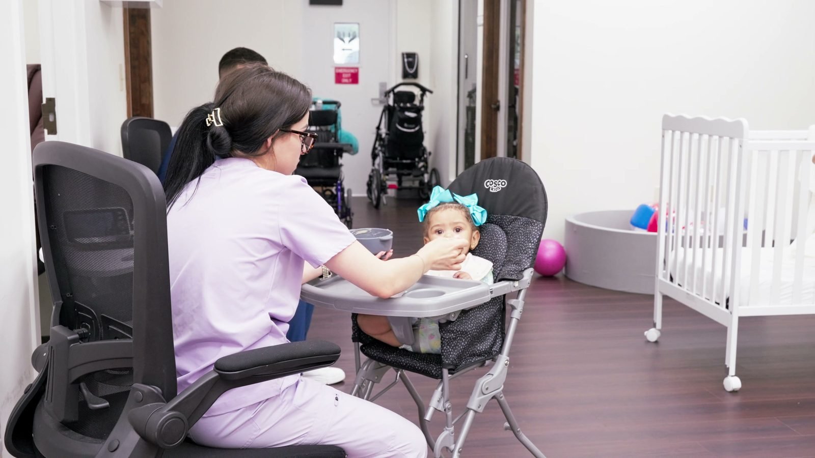 Nurse feeding a baby seated in an infant chair at Little Giants PPEC in Tampa, FL