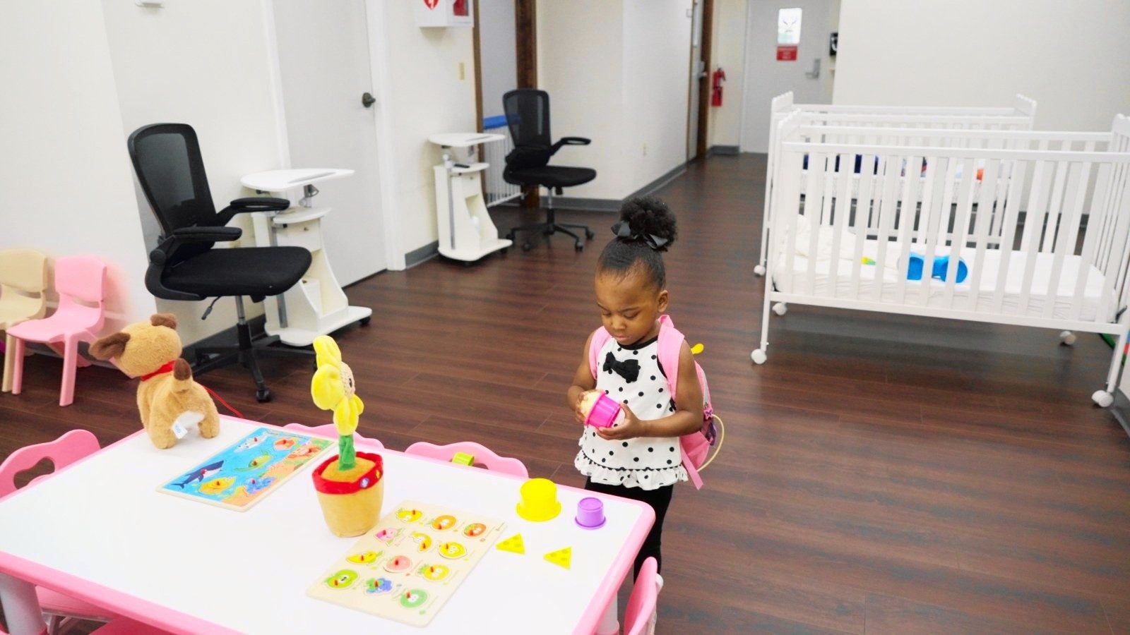 Young girl with a backpack playing at a pink activity table in a classroom at Little Giants PPEC in Tampa, FL